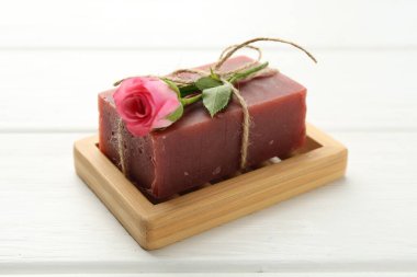 Sabun çubuğu ve beyaz ahşap masada güzel bir gül, yakın plan.