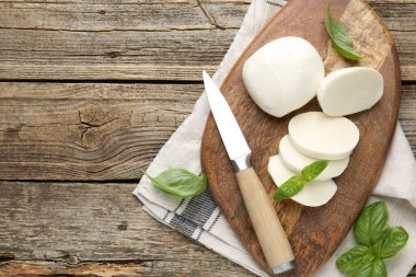 Ahşap masada fesleğen ve bıçakla mozzarella peyniri kes. Metin için boşluk