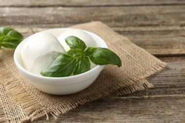 Ahşap masada mozzarella peyniri ve fesleğen, yakın plan. Metin için boşluk