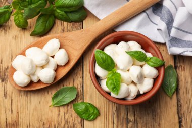 Mozzarella peyniri topları ve fesleğen ahşap masada, düz yatıyordu.