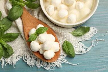 Mozzarella peyniri topları ve fesleğen mavi ahşap masada, düz yatıyordu.