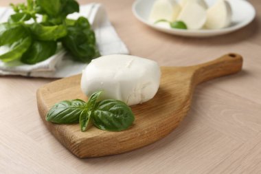 Ahşap masada mozzarella peyniri ve fesleğen, yakın plan.