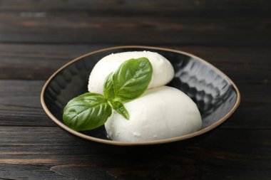 Nefis mozzarella peyniri ve fesleğen parçaları ahşap masada, yakın plan.