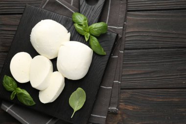 Ahşap masanın üstünde lezzetli mozzarella peyniri ve fesleğen parçaları. Metin için boşluk