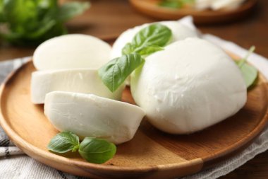 Nefis mozzarella peyniri parçaları ve fesleğen yaprakları ahşap masada, yakın plan.