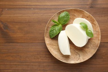 Ahşap masa üzerinde lezzetli mozzarella peyniri ve fesleğen yaprakları, üst manzara. Metin için boşluk