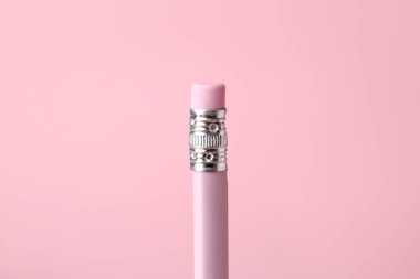 Pembe arka planda silgisi olan bir grafit kalem, yakın plan.