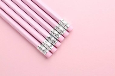 Pembe arka planda silgileri olan çizgili kalemler. Metin için boşluk