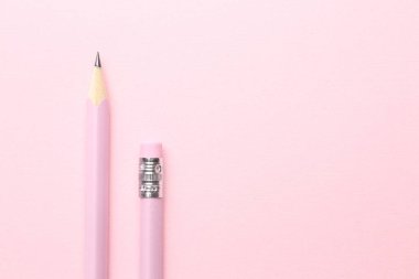 Pembe arka planda iki grafit kalem, düz. Metin için boşluk