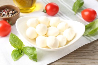 Lezzetli mozarella peynir topları, domatesler, fesleğen, yağ ve biberler ahşap masada, yakın plan.