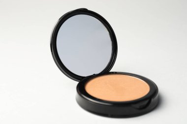 Açık gri arkaplanda ayna ile yüz pudrası, yakın plan