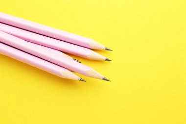 Many graphite pencils on yellow background, closeup. Space for text