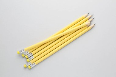 Açık gri arkaplanda silgileri olan bir sürü grafit kalem, düz konum