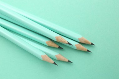 Turkuaz arka planda birçok grafit kalem, yakın plan