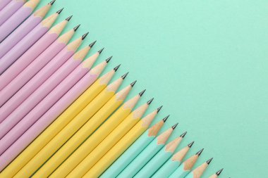 Turkuaz arka planda bir sürü grafit kalem, düz bir zemin. Metin için boşluk