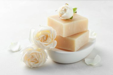 Aromatik sabun çubukları ve güller ışık masasında.