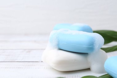 Beyaz ahşap masada köpüklü sabun çubukları, yakın plan. Metin için boşluk