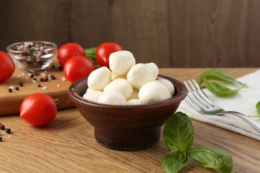 Lezzetli mozarella topları, domatesler, biberler ve fesleğenler ahşap masada, yakın plan.