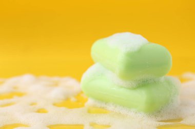 Sarı arka planda köpüklü sabun çubukları, yakın plan. Metin için boşluk