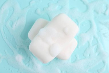 Açık mavi arka planda köpüklü sabun çubukları, üst görünüm