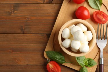 Lezzetli mozzarella topları, domates ve fesleğen, ahşap masa, düz yatak. Metin için boşluk