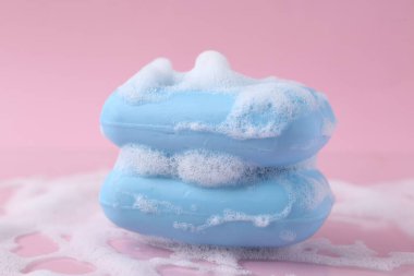 Pembe arka planda köpüklü sabun çubukları, yakın plan.