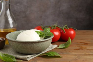 Lezzetli mozarella topları, domatesler, ahşap masada yağ ve fesleğen, yakın plan.