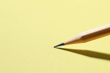 Sarı arka planda bir grafit kalem, yakın plan. Metin için boşluk