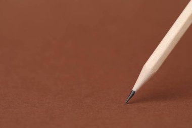 Kahverengi arka planda bir grafit kalem, yakın plan. Metin için boşluk