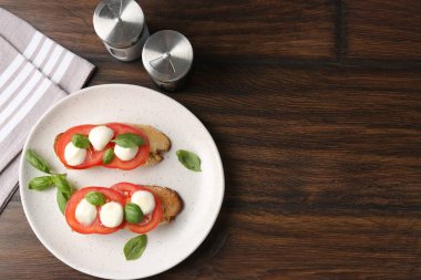 Peynirli, domatesli, ahşap masadaki fesleğenli lezzetli sandviçler. Metin için boşluk