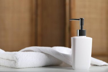 Şişede sıvı sabun ve beyaz masa içinde havlu.