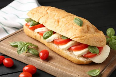 Mozarella peynirli, domatesli, fesleğenli, siyah ahşap masa, yakın plan.