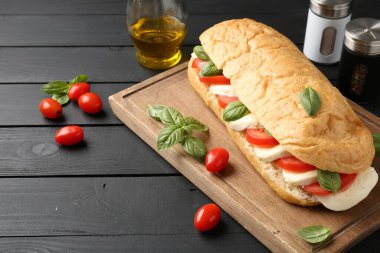 Mozarella peynirli, domatesli, fesleğenli, siyah ahşap masa, yakın plan.