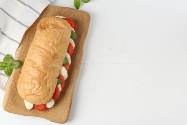 Mozarella peynirli, domatesli, fesleğenli, beyaz ahşap masa, düz yatak. Metin için boşluk