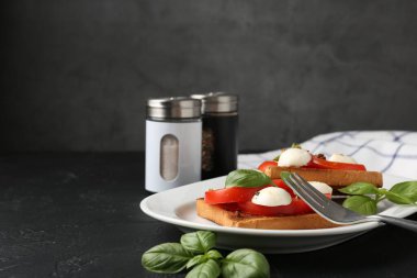 Mozarella peynirli, domatesli, fesleğenli ve çatallı lezzetli sandviçler gri arka planda, yakın planda. Metin için boşluk