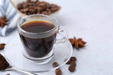 Bir fincan aromatik kahve, fasulye ve yıldız anason beyaz masada, yakın plan. Metin için boşluk