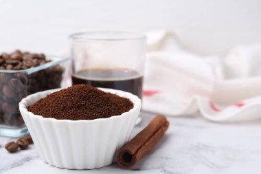 Kasedeki kahve tozu, tarçın çubuğu, fasulye ve içecek beyaz mermer masada, yakın plan. Metin için boşluk