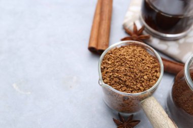 Granüle edilmiş hazır kahve, ölçü kabı ve baharatlar gri masada, yakın plan. Metin için boşluk