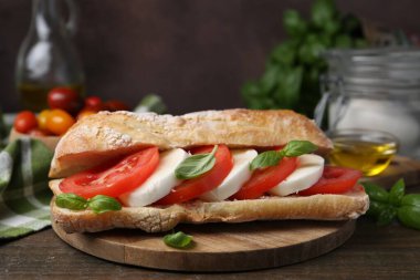 Mozarella peynirli, domatesli ve fesleğenli lezzetli sandviç kahverengi arka planda, yakın planda.