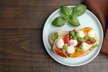 Mozarella peynirli, domatesli ve ahşap masadaki fesleğenli lezzetli sandviç. Metin için boşluk