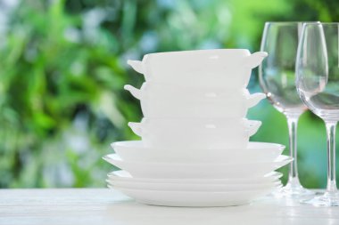 Bulanık yeşil arka planda beyaz masada farklı temiz tabaklar