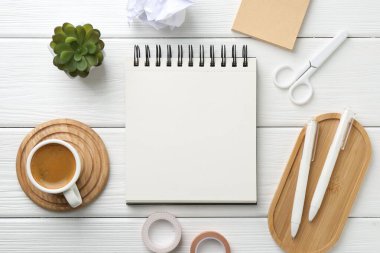 Düz kompozisyon ve beyaz ahşap masa üzerinde boş bir defter.