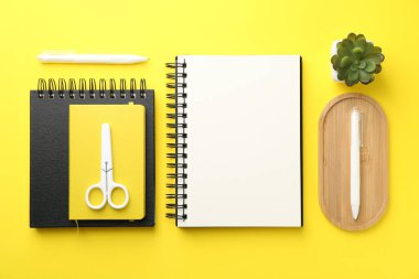 Düz kompozisyon, sarı arkaplanda boş bir defter.