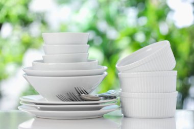 Bulanık yeşil arka planda beyaz masada farklı temiz tabaklar