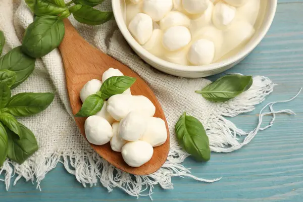 Mozzarella peyniri topları ve fesleğen mavi ahşap masada, düz yatıyordu.
