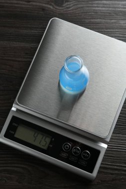Tahta sehpanın üzerinde numune şişesi olan laboratuvar ölçeği, üst görünüm.