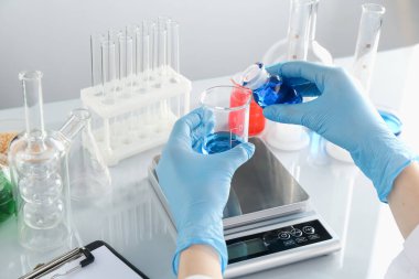 Laboratuvardaki beyaz ayna masasında numune ve terazilerle çalışan bilim adamı.