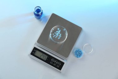 Petri kabı ve diğer laboratuvar camlarıyla beyaz masa üzerinde renk ışıklarıyla ölçeklendir, düz uzan