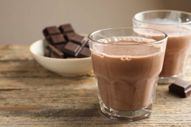 Bardakta çikolatalı süt ve ahşap masada parçalar, yakın plan. Metin için boşluk