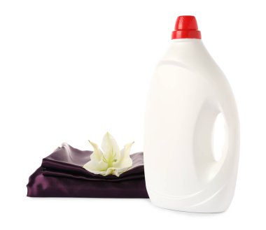 Bir şişe yumuşatıcı, üst üste yığılmış giysiler ve beyaz bir çiçek.
